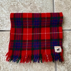 May include: Red, green, and blue plaid blanket with fringe. The blanket has a label that says "Kynoch" and "Pure New Wool" in white text.