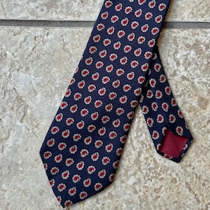 Op de afbeelding: Een donkerblauwe stropdas met een paisley-patroon in rood en wit.