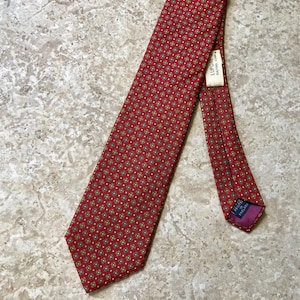 May include: A red patterned silk tie with a small tag that reads "Lupone Silk 100%".