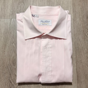 May include: A light pink long-sleeve dress shirt featuring a pointed collar and a pleated front placket. The interior label reads Ben Silver Charleston Fine Shirtings Made in Canada, with a size tag indicating 16-34. The shirt is folded neatly.