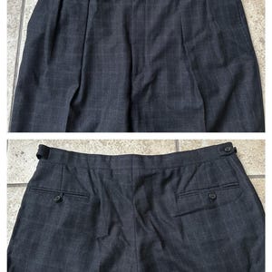 May include: A pair of dark gray plaid pants with pleats and button closures. The pants have two back pockets with buttons.