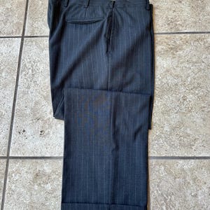 May include: Dark gray pinstripe pants with a cuffed hem.