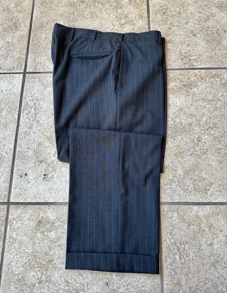 May include: Dark gray pinstripe pants with a cuffed hem.