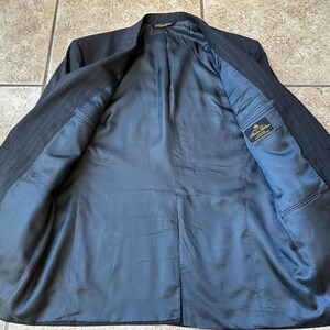 May include: A black pinstripe suit jacket with a blue lining. The lining has a small label that reads "Brooks Brothers".