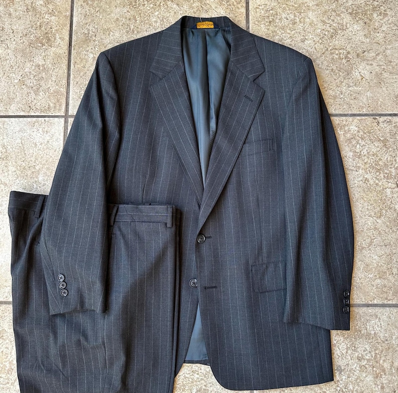 May include: A dark gray pinstripe suit with a single-breasted jacket and matching pants.