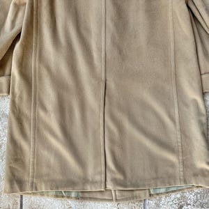 May include: A tan-colored coat with a classic design. The coat features a tailored silhouette with a notched collar and long sleeves. The fabric appears to be a soft, suede-like material. The coat is suitable for cooler weather and provides a stylish layer.