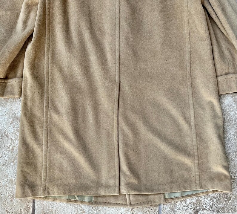 May include: A tan-colored coat with a classic design. The coat features a tailored silhouette with a notched collar and long sleeves. The fabric appears to be a soft, suede-like material. The coat is suitable for cooler weather and provides a stylish layer.