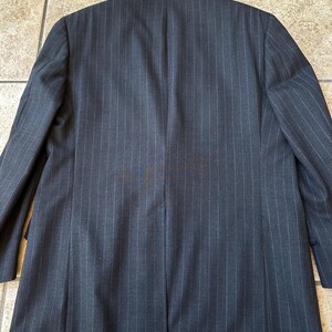 May include: A dark gray pinstripe blazer with a single button closure. The blazer has a classic fit and is made of a high-quality fabric.