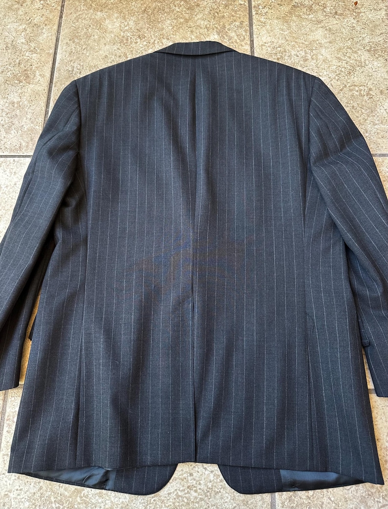 May include: A dark gray pinstripe blazer with a single button closure. The blazer has a classic fit and is made of a high-quality fabric.