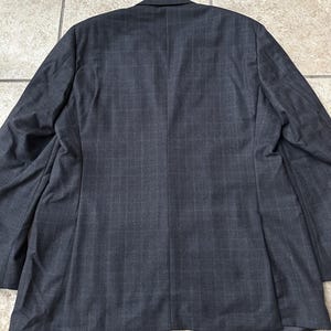 May include: A dark gray blazer with a subtle pinstripe pattern. The blazer has a single-breasted closure and a notch lapel.
