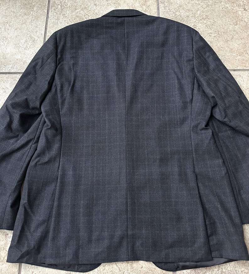 May include: A dark gray blazer with a subtle pinstripe pattern. The blazer has a single-breasted closure and a notch lapel.