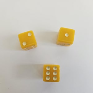 May include: Three yellow dice with white dots are scattered on a white surface. The dice show different numbers, including one, two, and six. The dice are a solid, opaque yellow color.