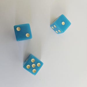May include: Three light blue dice with ivory-colored dots are scattered on a white surface. Each die has a different number of dots visible, ranging from two to six. The dice are slightly angled, showcasing their cube shape.