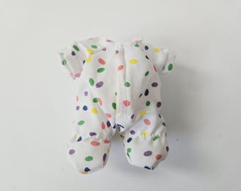 May include: A white one-piece garment with short sleeves and enclosed feet, featuring a scattered pattern of small, oval-shaped polka dots in shades of yellow, green, pink, purple, and blue, with a vertical seam running down the center front.