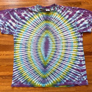 May include: A tie-dye t-shirt with a circular pattern in shades of purple, blue, green, and white.