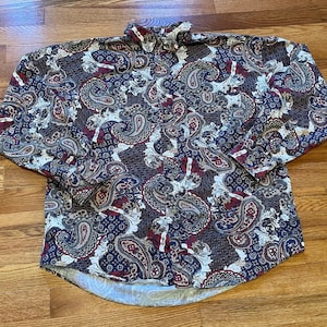 May include: A long-sleeved button-down shirt with a paisley pattern in shades of blue, red, and white.