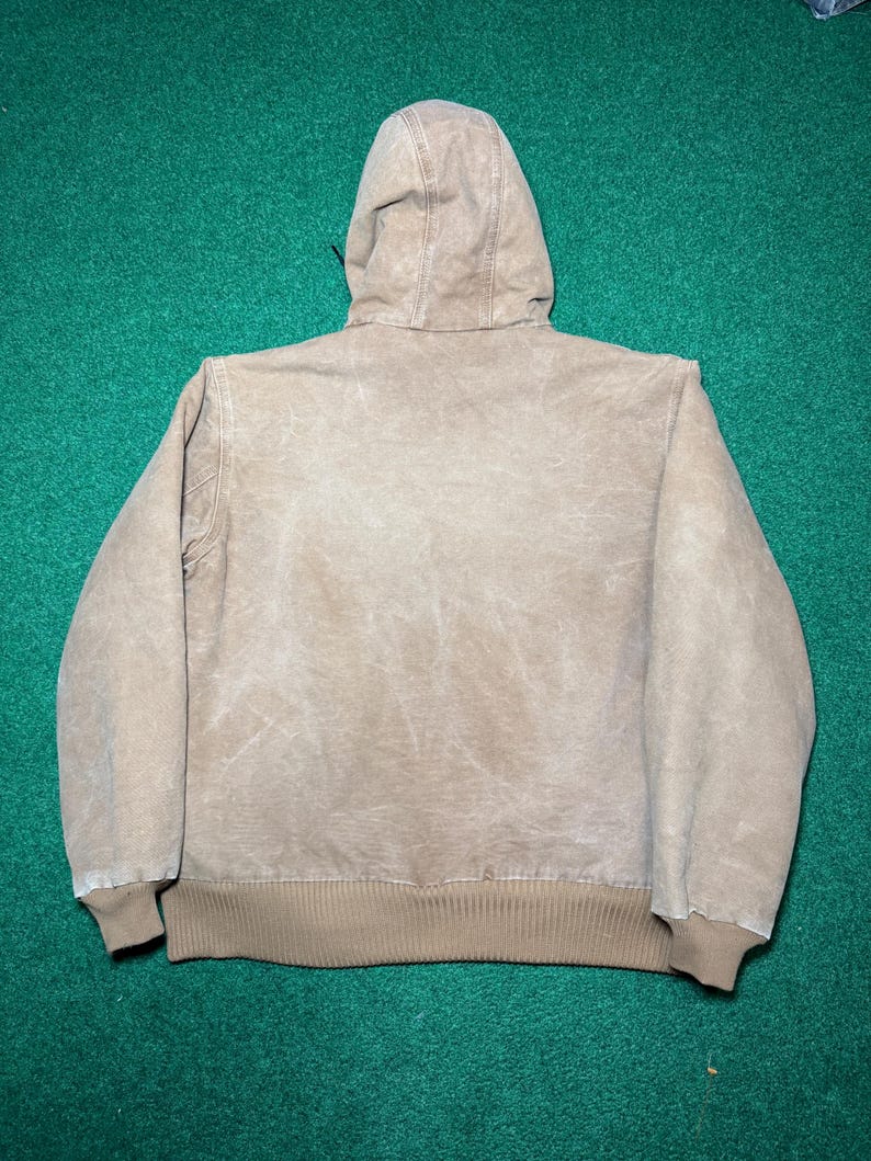 Puede incluir: Chaqueta con capucha de color beige con cord&oacute;n, pu&ntilde;os y cintura de canal&eacute;. La chaqueta est&aacute; hecha de un material duradero y desgastado, y la capucha est&aacute; sujeta a la espalda.