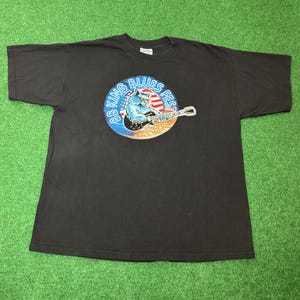 May include: Black t-shirt featuring a circular graphic with a blue wolf playing a guitar, the text "88 King Blues Fest" and the American flag. The year "2000" is also printed on the graphic.