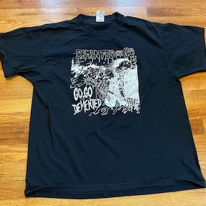 May include: Black t-shirt with a white graphic print of a skull and the text "DEMENTED FOR LIFE" and "GO,GO DEMENTED".