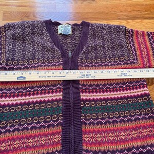 May include: A purple, red, green, and white striped knit cardigan with a zipper closure. The cardigan has a fair isle pattern and the text "Do you have it all covered?" is printed on a ruler.