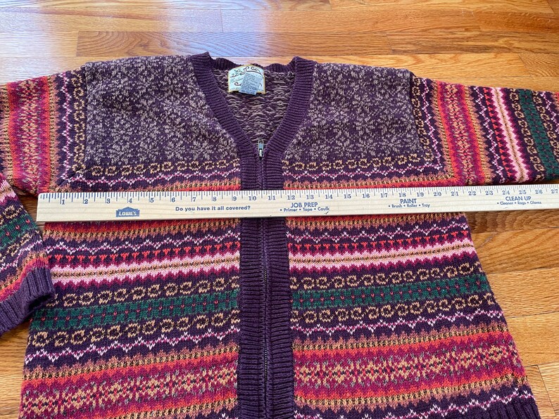 May include: A purple, red, green, and white striped knit cardigan with a zipper closure. The cardigan has a fair isle pattern and the text "Do you have it all covered?" is printed on a ruler.