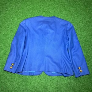 May include: A vibrant royal blue blazer with gold buttons. The back view highlights the tailored cut and button placement on the sleeves. The jacket is made from a smooth, possibly wool, fabric.