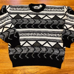 May include: Black and white striped sweater with a geometric pattern. The sweater has a crew neck and long sleeves. The brand name "Carlisle" is visible on the tag.