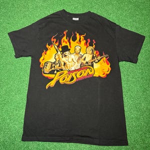 May include: Black t-shirt featuring a graphic of a band with flames and the word "Poison" in yellow and red. The band members are depicted with guitars and a microphone. The shirt is made of a soft material.