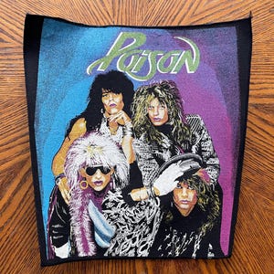 May include: A black fabric patch with a colorful image of a rock band called "Poison". The band members are wearing colorful clothing and have long hair. The background is a gradient of blue, purple, and pink.