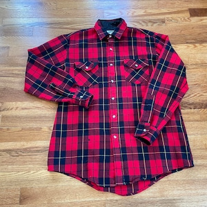 May include: A red, black, and yellow plaid flannel shirt with long sleeves and a button-down front.