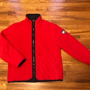 May include: Red quilted fleece jacket with a black zipper and a Tommy Hilfiger logo patch on the right sleeve.