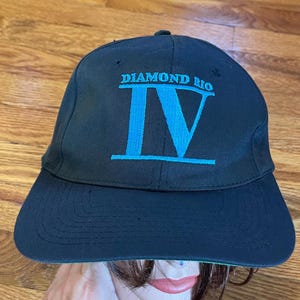 May include: Black baseball cap with a blue embroidered logo that says "Diamond Rio IV".