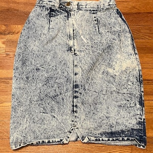 May include: A blue denim skirt with a white acid wash pattern. The skirt has a high waist and a straight silhouette.