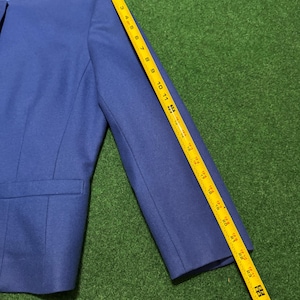 May include: A blue blazer with a notched collar and a single-button closure. The sleeve length is approximately 61 cm. The blazer has a pocket on the left side.