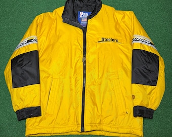 Puede incluir: Chaqueta amarilla de los Steelers con cuello y mangas negras. La chaqueta tiene una cremallera completa y la palabra "Steelers" está impresa en el pecho. Las mangas tienen paneles negros y rayas blancas y negras.