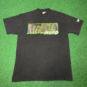 May include: Black t-shirt with a graphic featuring figures in green and brown, with the word "MUDD" in green. The shirt has short sleeves and a crew neck. The brand name "Wiz" is printed on the right sleeve.