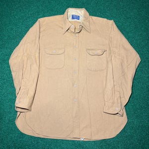 Op de afbeelding: Een bruin overhemd met knopen, twee borstzakken en een kraag. Het shirt met lange mouwen heeft manchetten met knopen en een afgeronde zoom. Het shirt is gemaakt van een zachte, geweven stof. Een klein label is zichtbaar op de kraag.