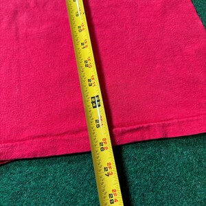 May include: A close-up of a pink fabric with a yellow measuring tape. The tape measures 29 inches.