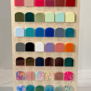 May include: A wooden display board featuring acrylic color options. The board is labeled "By His Saving Grace Acrylic Options" and showcases various colors like pink, blue, green, and orange. Each color is labeled with its name.