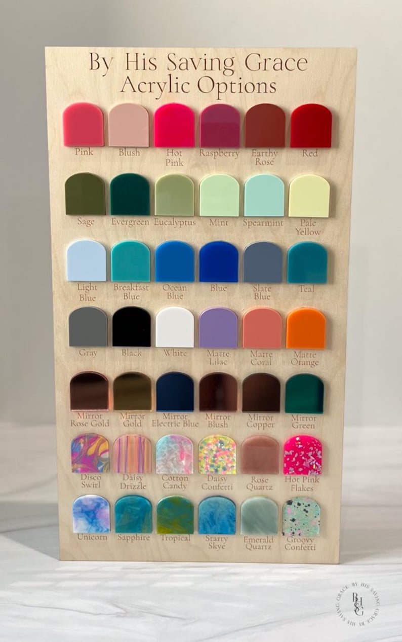 May include: A wooden display board featuring acrylic color options. The board is labeled "By His Saving Grace Acrylic Options" and showcases various colors like pink, blue, green, and orange. Each color is labeled with its name.