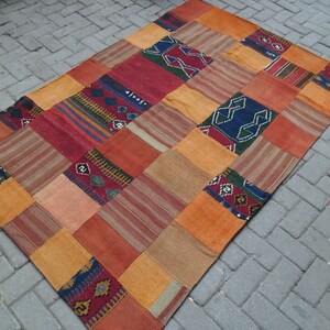 Pode incluir: Um tapete de patchwork com uma variedade de cores e padrões, incluindo vermelho, laranja, amarelo, azul e verde. O tapete é feito de tecido tecido e tem uma forma retangular.