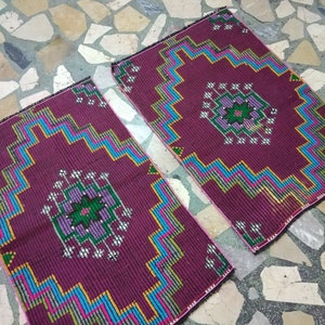 Puede incluir: Dos alfombras color burdeos con patrones geom&eacute;tricos en tonos azules, verdes, rosas y amarillos. Las alfombras tienen un dise&ntilde;o central con un motivo floral.