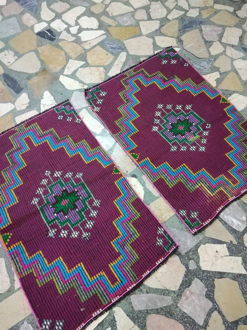 Puede incluir: Dos alfombras color burdeos con patrones geom&eacute;tricos en tonos azules, verdes, rosas y amarillos. Las alfombras tienen un dise&ntilde;o central con un motivo floral.