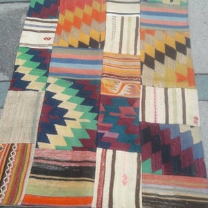 Puede incluir: Una alfombra de patchwork colorida hecha de diferentes telas. La alfombra está compuesta por cuadrados y rectángulos de varios colores y patrones, incluyendo rojo, naranja, amarillo, verde, azul y marrón. La alfombra es una pieza única y ecléctica de decoración del hogar.