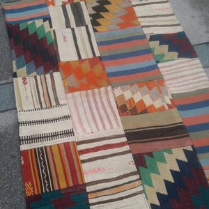 Puede incluir: Una alfombra de patchwork colorida con varios patrones geométricos en tonos de rojo, naranja, azul, verde, marrón y blanco.