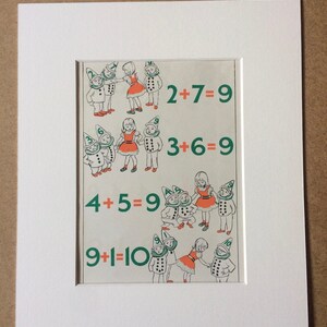May include: A framed vintage print featuring children and gnomes illustrating basic addition problems. The equations 2+7=9, 3+6=9, 4+5=9, and 9+1=10 are displayed in green text. The artwork is set within a white mat.