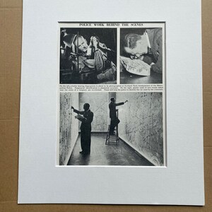 以下が含まれることがあります： 「POLICE WORK BEHIND THE SCENES」と題された、額装された白黒プリント。 指紋写真や証拠を調べる刑事など、警察の仕事の様子が描かれています。 下部のテキストはシーンについて説明しています。