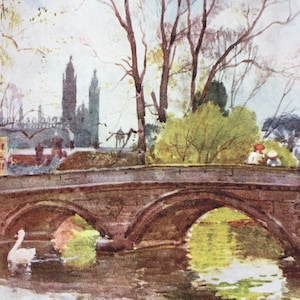May include: A watercolour painting depicting a stone bridge with three arches spanning a river. Two swans swim in the water. Trees and buildings form the backdrop. Two figures sit on the bridge. The painting has a soft colour palette.