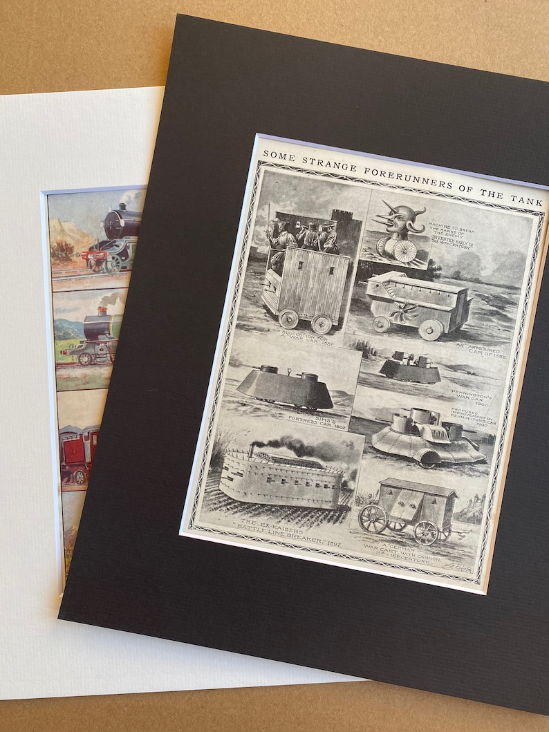 May include: A framed print showing historical illustrations of early tank concepts and steam locomotives. The print is matted in black and white, with the text "SOME STRANGE FORERUNNERS OF THE TANK". The image is on a white background.
