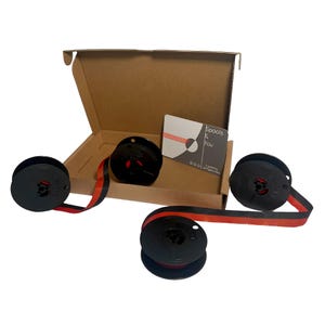 May include: A set of black typewriter ribbon spools with red and black ribbon, displayed with a cardboard box and a card that reads "Spools & You". The spools are arranged on a white surface.